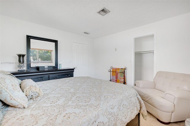 bedroom featuring visible vents, a textured ceiling, and a closet