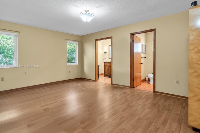 11472 SW 28th Ter, Miami, FL 33165 - unfurnished bedroom featuring light wood-type flooring, connected bathroom, and a textured ceiling