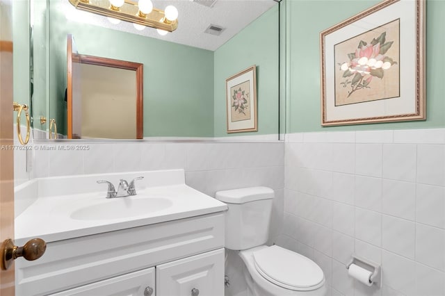 11472 SW 28th Ter, Miami, FL 33165 - bathroom with tile walls, vanity, toilet, a wainscoted wall, and a textured ceiling