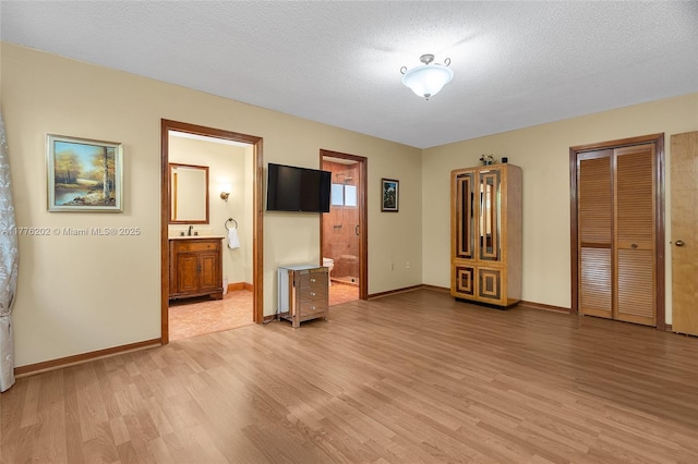 11472 SW 28th Ter, Miami, FL 33165 - unfurnished bedroom with light wood-style floors, baseboards, a sink, and a textured ceiling
