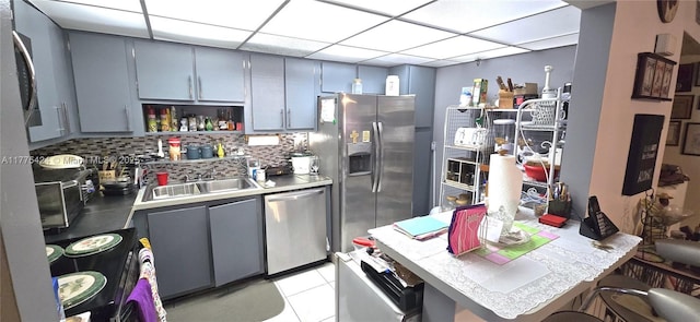 kitchen featuring a sink, stainless steel appliances, gray cabinets, tasteful backsplash, and light countertops
