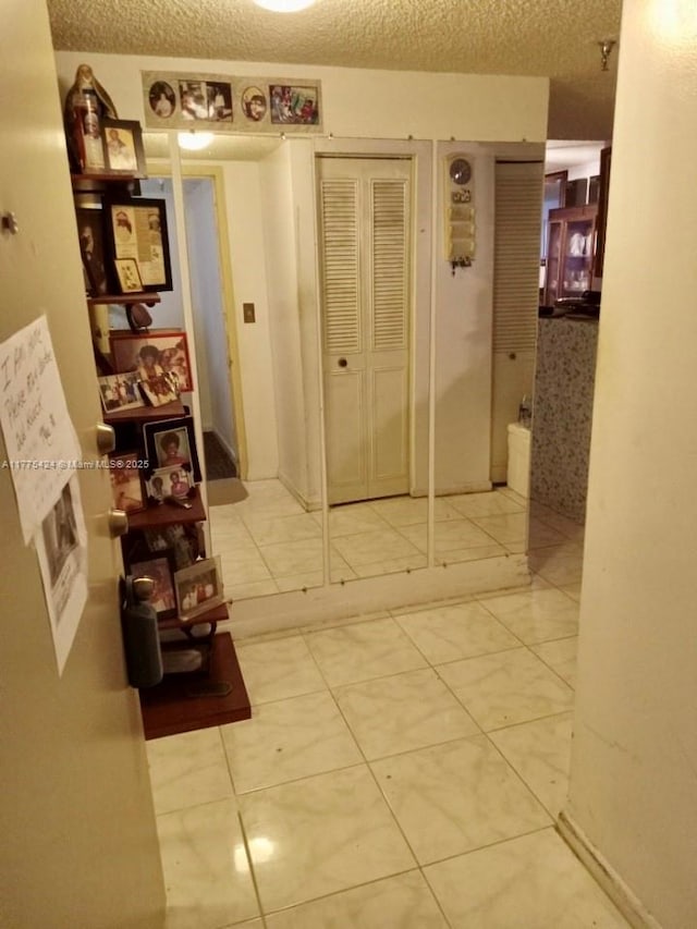 hallway with a textured ceiling and tile patterned floors
