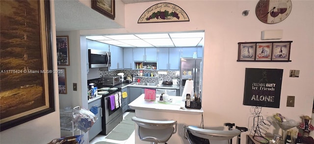 kitchen featuring a sink, stainless steel appliances, a kitchen breakfast bar, a peninsula, and light countertops