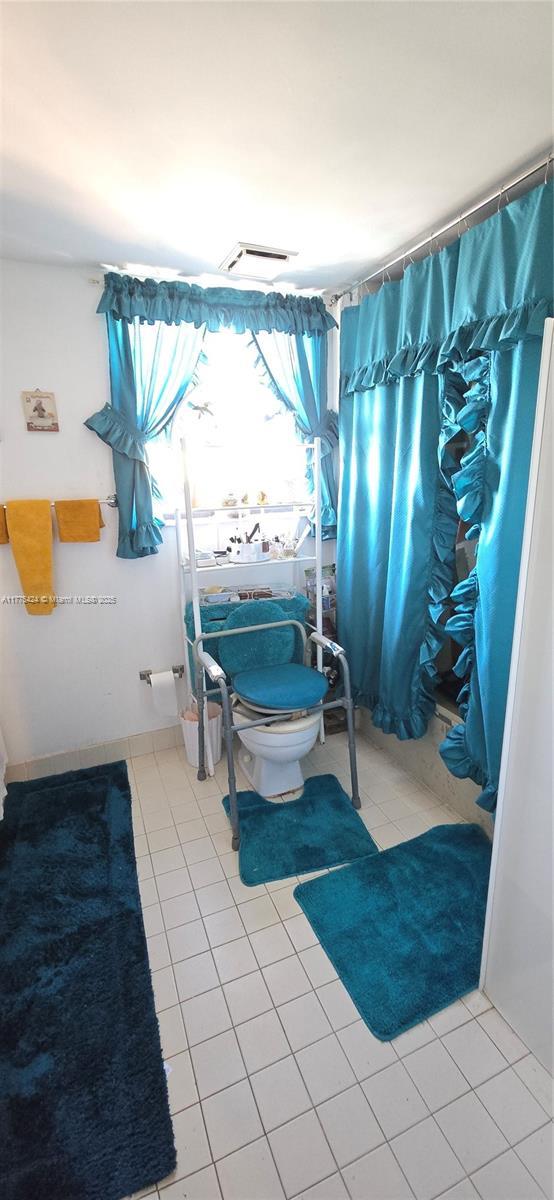 bathroom with toilet, a shower with curtain, and tile patterned flooring