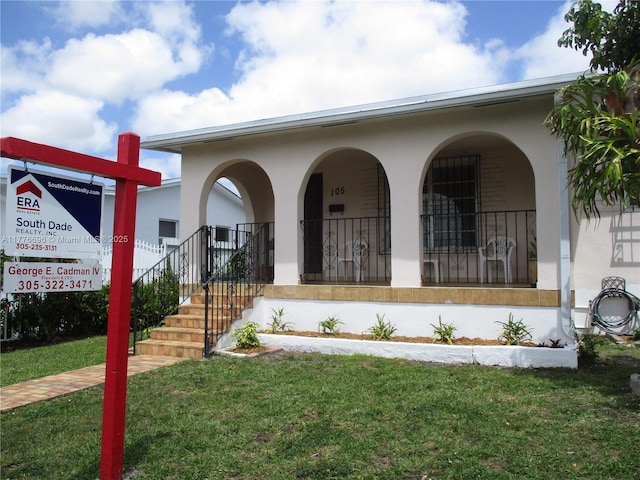 105 NW 32nd Pl, Miami, FL 33125 - view of front of home featuring covered porch, a front lawn, and stucco siding