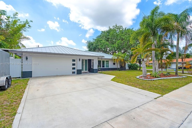 single story home featuring an attached garage, concrete driveway, a front yard, stucco siding, and french doors