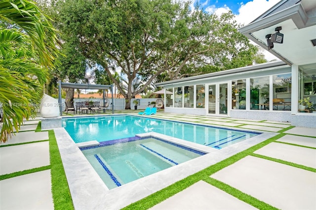 view of pool featuring fence, french doors, a pool with connected hot tub, and a patio area