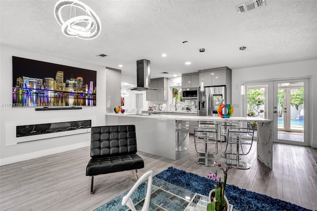 living area featuring light wood-type flooring, a textured ceiling, french doors, and visible vents