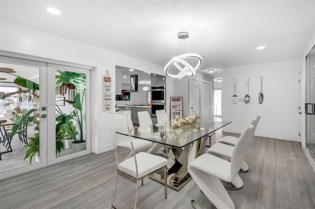 dining room featuring light wood finished floors, baseboards, and a notable chandelier