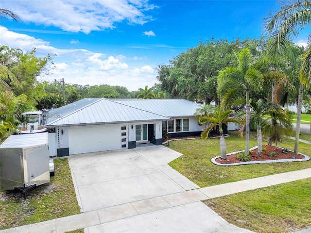 ranch-style house with a front yard, concrete driveway, stucco siding, metal roof, and a garage