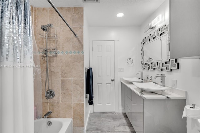 bathroom featuring double vanity, visible vents, a sink, and shower / bath combo