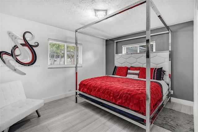 bedroom with a textured ceiling, baseboards, and wood finished floors