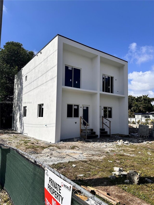 rear view of property featuring stucco siding and entry steps