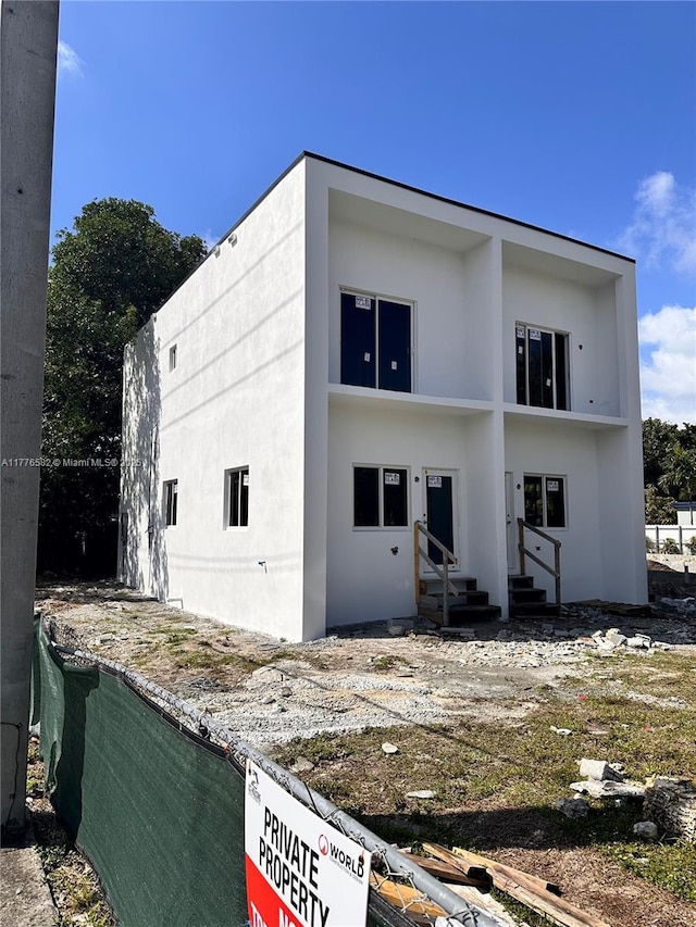 back of property with stucco siding and entry steps