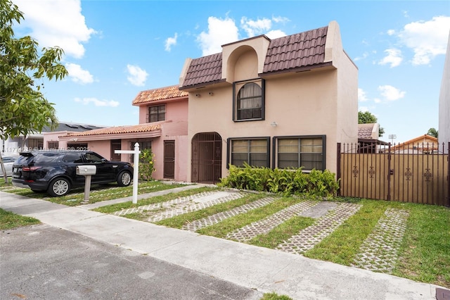 view of front of property featuring driveway, fence, stucco siding, and a tile roof