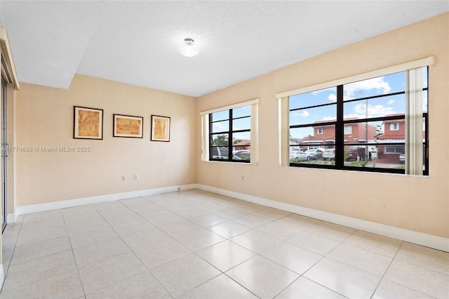 empty room featuring baseboards and light tile patterned flooring