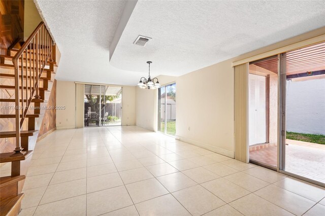 spare room with light tile patterned floors, an inviting chandelier, visible vents, stairway, and baseboards