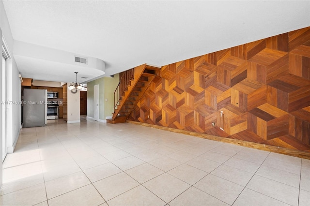 unfurnished living room featuring visible vents, stairway, an inviting chandelier, and light tile patterned floors