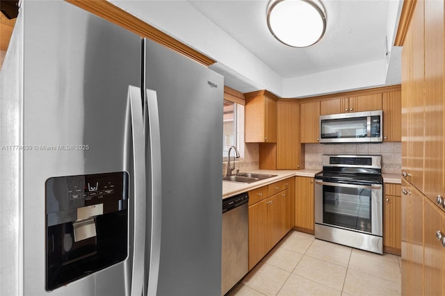 kitchen featuring light tile patterned floors, tasteful backsplash, light countertops, a sink, and stainless steel appliances