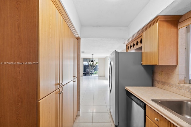 kitchen featuring an inviting chandelier, backsplash, light tile patterned flooring, stainless steel dishwasher, and tile countertops