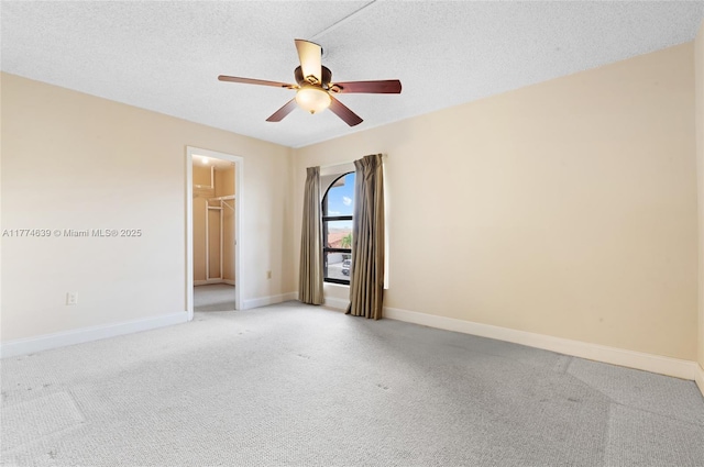 unfurnished room with a textured ceiling, ceiling fan, baseboards, and light colored carpet