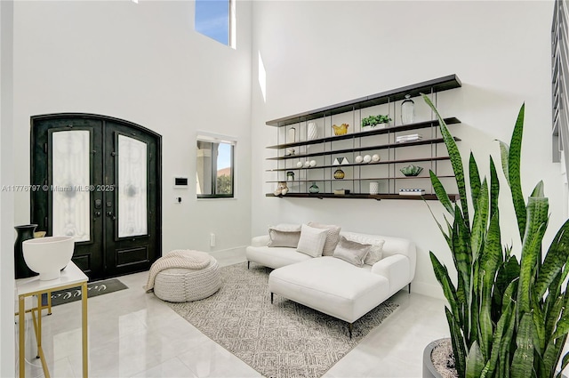 living area with baseboards, a high ceiling, and french doors