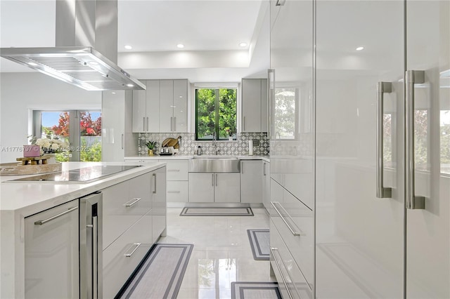 kitchen with island range hood, a sink, modern cabinets, and electric cooktop