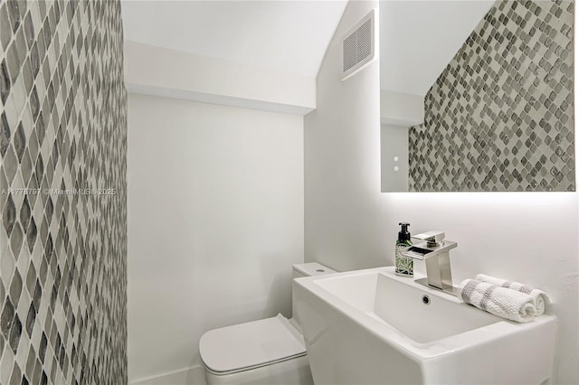 half bath featuring visible vents, toilet, and a sink