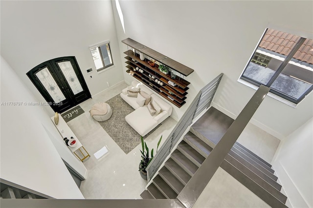 foyer featuring stairs, a towering ceiling, french doors, and baseboards