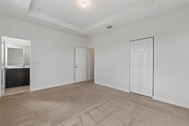 10861 W 32nd Ln Unit 10861, Hialeah, FL 33018 - unfurnished bedroom featuring light carpet, a tray ceiling, baseboards, and ensuite bathroom