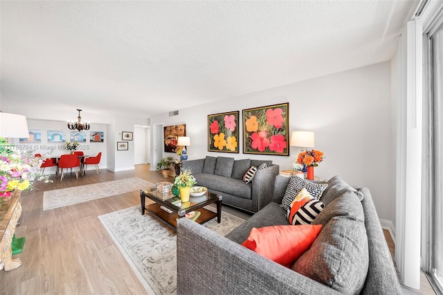 13131 Ixora Ct Unit A-1 A-2 A-3, North Miami, FL 33181 - living area featuring an inviting chandelier, light wood-style flooring, a textured ceiling, visible vents, and baseboards