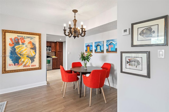 13131 Ixora Ct Unit A-1 A-2 A-3, North Miami, FL 33181 - dining room with light wood-style flooring, a textured ceiling, a notable chandelier, and baseboards