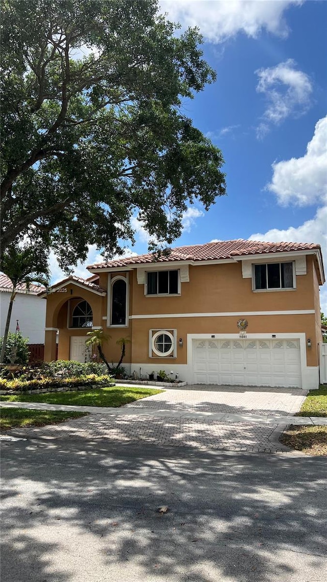 view of front of home featuring a tiled roof, decorative driveway, a garage, ac unit, and stucco siding