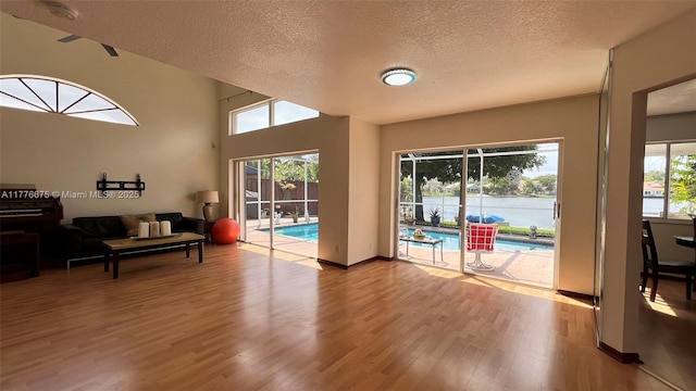 living area featuring baseboards, a textured ceiling, a healthy amount of sunlight, and wood finished floors