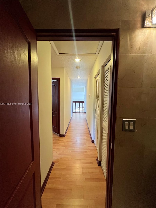 hall featuring baseboards and light wood-type flooring