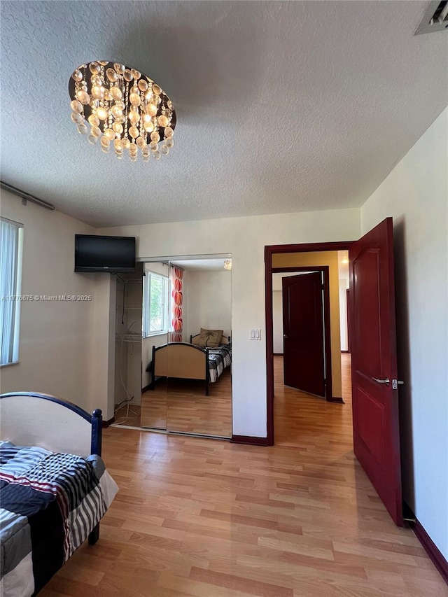 bedroom with baseboards, light wood-type flooring, visible vents, and a textured ceiling