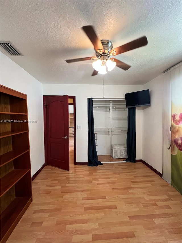 unfurnished bedroom with baseboards, a textured ceiling, light wood finished floors, ceiling fan, and visible vents