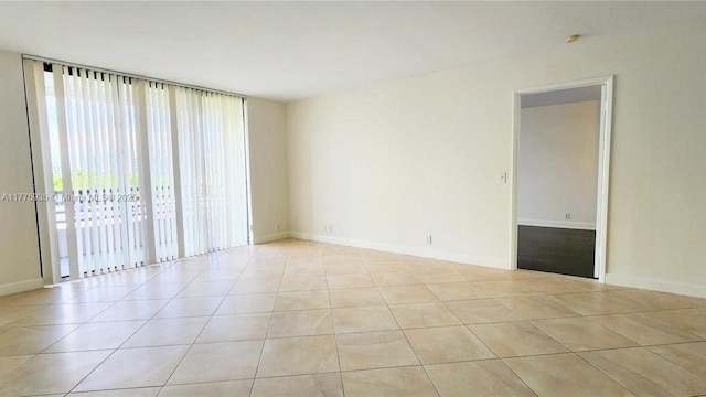 unfurnished room with light tile patterned flooring and baseboards