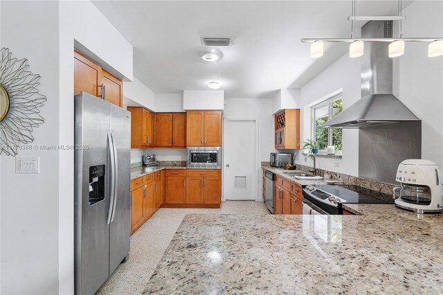 10619 NE 10th Pl, Miami Shores, FL 33138 - kitchen featuring appliances with stainless steel finishes, extractor fan, light stone countertops, brown cabinets, and pendant lighting