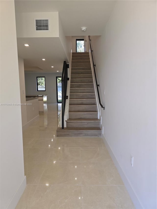 staircase with visible vents, baseboards, marble finish floor, and plenty of natural light