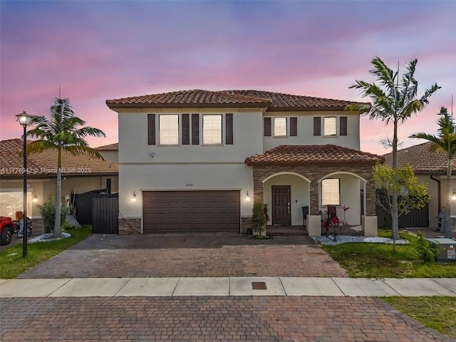23703 SW 116th Ct, Homestead, FL 33032 - mediterranean / spanish house featuring stone siding, a tiled roof, decorative driveway, stucco siding, and covered porch