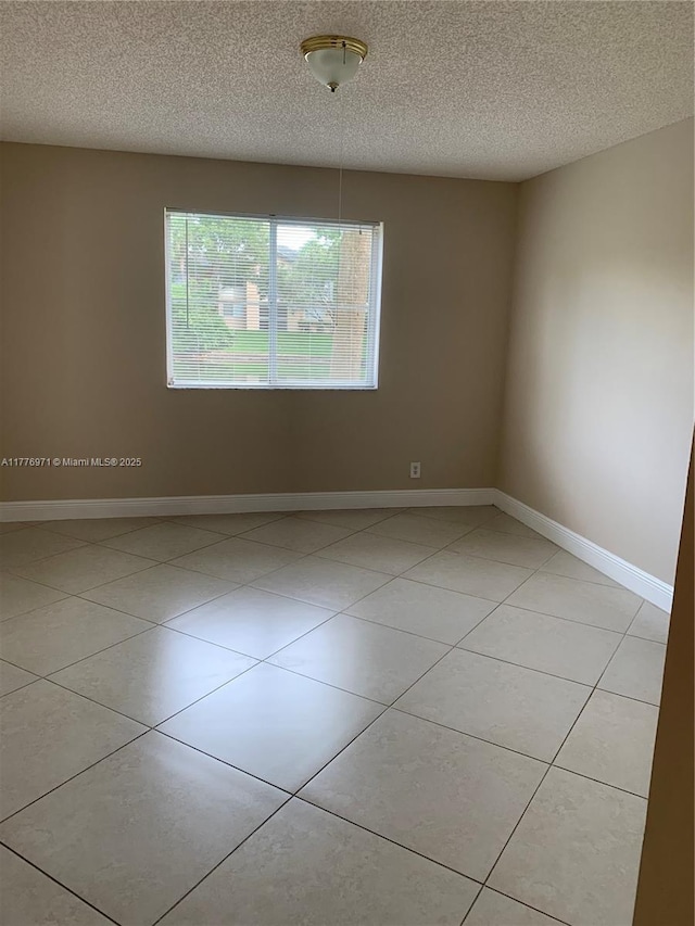 unfurnished room featuring baseboards, a textured ceiling, and light tile patterned floors