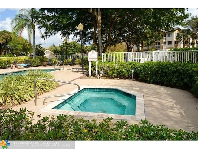 community pool featuring a hot tub, fence, and a patio