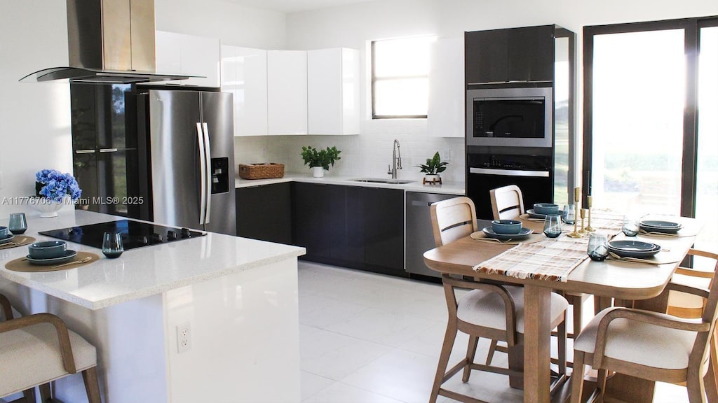 kitchen featuring island exhaust hood, modern cabinets, a sink, white cabinets, and black appliances