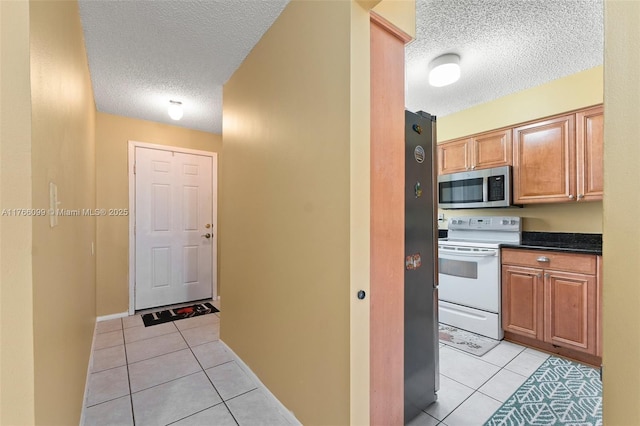 6034 Indrio Rd Unit 7, Fort Pierce, FL 34951 - kitchen featuring a textured ceiling, light tile patterned floors, dark countertops, and stainless steel appliances