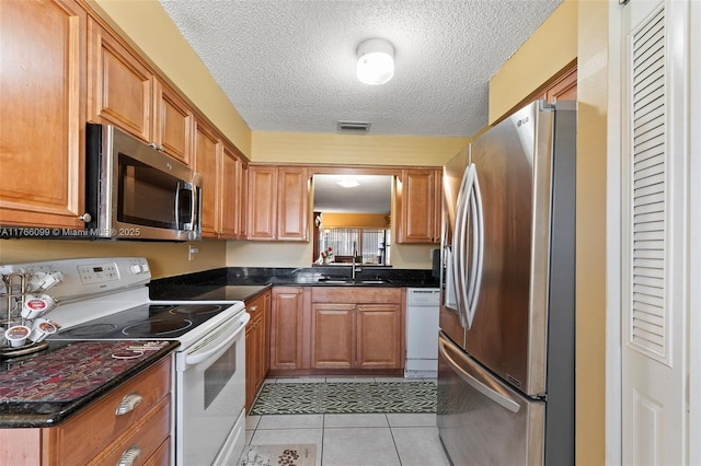 6034 Indrio Rd Unit 7, Fort Pierce, FL 34951 - kitchen featuring light tile patterned floors, visible vents, appliances with stainless steel finishes, a sink, and dark countertops