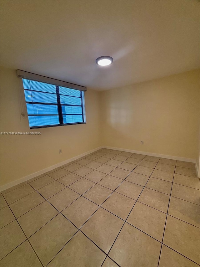 empty room featuring baseboards and light tile patterned floors