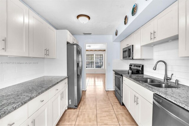 1910 NE 56th St, Fort Lauderdale, FL 33308 - kitchen with stainless steel appliances, a sink, white cabinetry, and backsplash