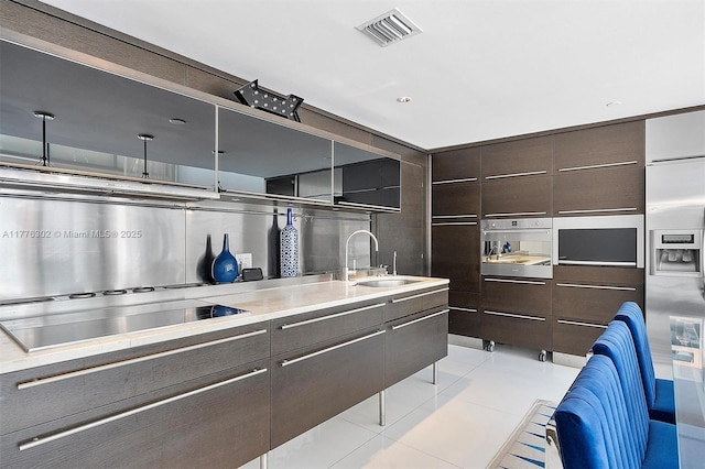 kitchen with visible vents, appliances with stainless steel finishes, tasteful backsplash, a sink, and light countertops