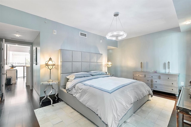 bedroom featuring a notable chandelier, visible vents, and wood finished floors